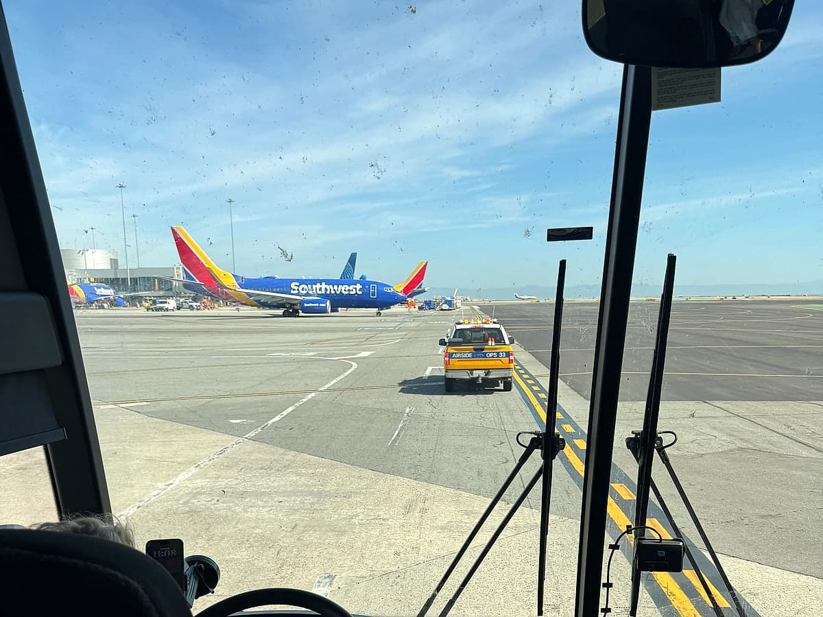 The view through a Landline coach's windscreen on the SFO ramp, following an airport operations truck past parked aircraft.
